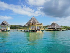 Resort tropical sobre el agua con bungalow de techo de paja, mar Caribe